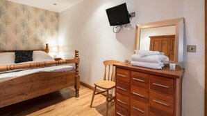 A bedroom with a wooden bed, a wooden dresser, a chair, and a television mounted on the wall. - Luxury 1bedroom Lodge in Prestwich (Manchester)