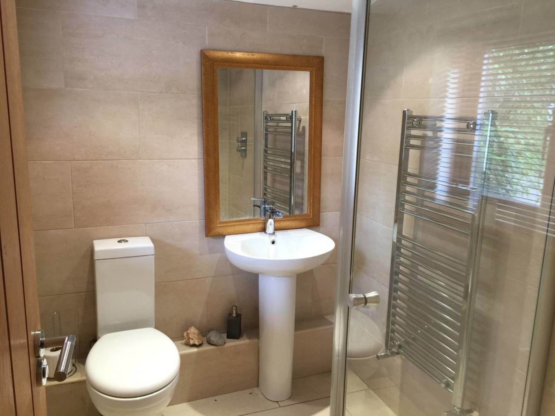 A bathroom with a toilet, sink, and glass shower enclosure.