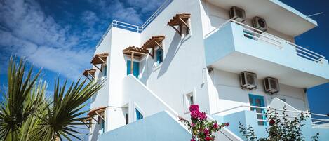 A multi-story building with a white facade, blue accents, and balconies.