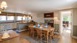 Une cuisine spacieuse avec des meubles en bois, une table à manger pour six personnes et une cheminée en pierre.