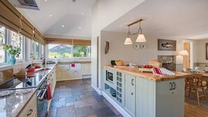 Une cuisine spacieuse dotée d’un îlot central, de grandes fenêtres et offrant une vue sur l’extérieur.