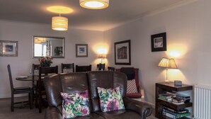 A living room with a leather sofa, dining table, chairs, and a bookshelf.