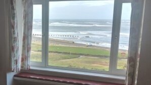 A room with a window overlooking a beach.
