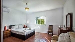Ein Schlafzimmer mit Bett, Nachttischen, einem Sessel, einem Schminktisch und einem Spiegel.