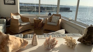 Una habitación acogedora con muebles de mimbre, vista al mar y caracolas decorativas.
