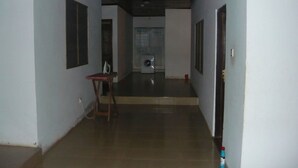 A hallway with a tiled floor, a wooden chair, a washing machine, and a door on the right. - 3 Bed House Sleeps 6 - Parking, Wifi, Generator (Kumasi)