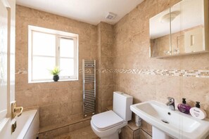 Bathroom features a toilet, sink, and mirror, with a window and towel rack.