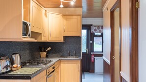 Una cocina con armarios de madera, encimera de granito, estufa y microondas.
