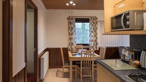 Una cocina compacta con una mesa de comedor, sillas de madera, un microondas y un tostador.