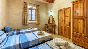 A room with two beds, wooden wardrobe, a mirror, and a window with curtains. - Villa Ta Debora Sleeps 7 With Pool (Xaghra)