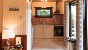 A compact kitchen with wooden cabinets, a window above the sink, and a sign on the wall. - Birch Lodge 23 With Hot Tub, Newton Stewart (Newton Stewart)