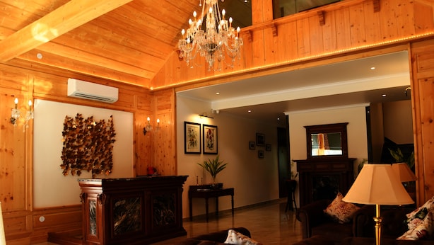 Un intérieur en bois agrémenté d’un lustre, d’une cheminée et d’un canapé.