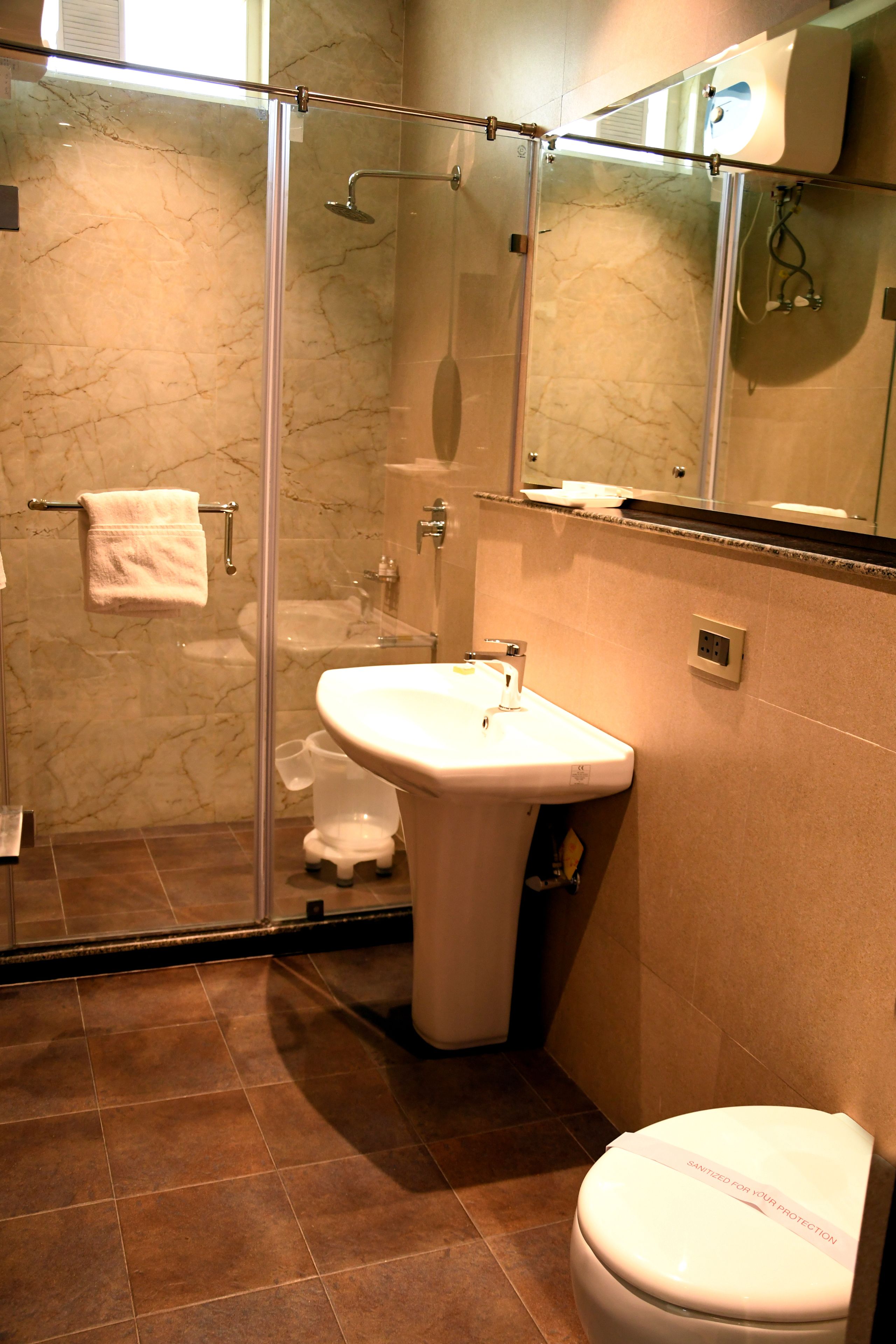 A bathroom with a glass-enclosed shower, a sink, and a toilet.