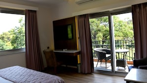 Une chambre d’hôtel comprenant un lit, un bureau avec une chaise, une télévision et un balcon avec une table et des chaises.
