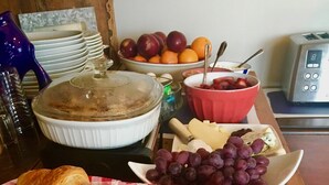 A breakfast buffet with croissants, muffins, bread, grapes, and cheese.
