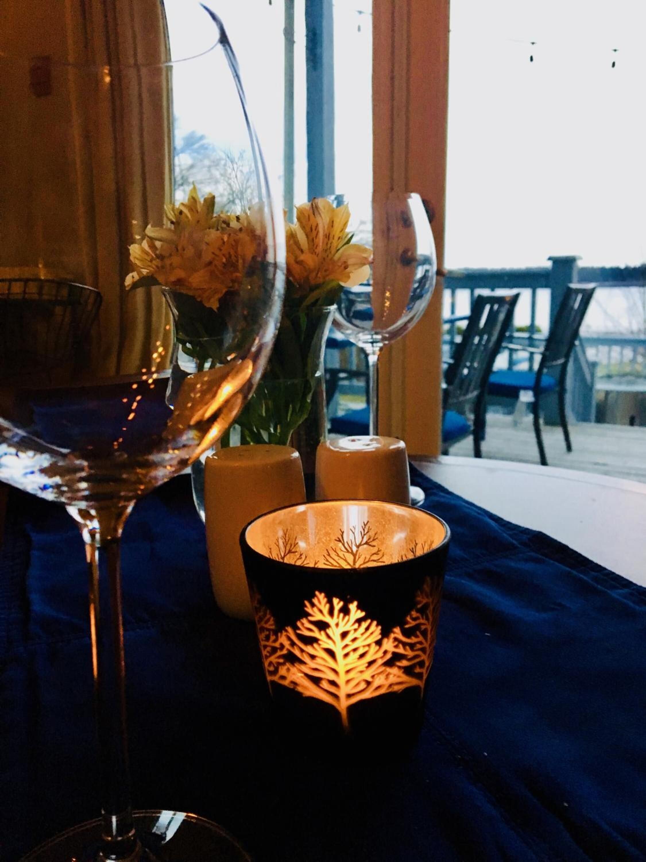 A table with a wine glass, a candle, and a decorative vase with flowers.