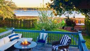 A deck with outdoor seating, a fire pit, and a view of the water.
