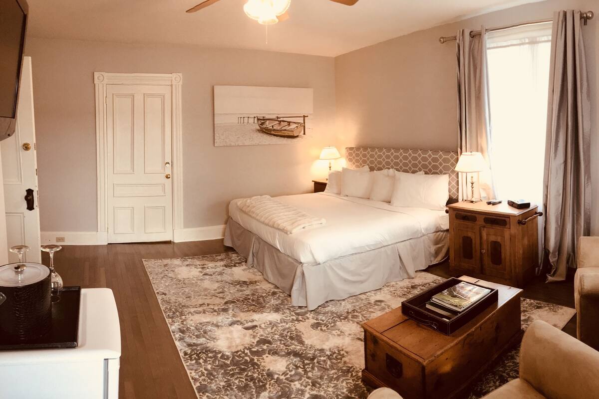 A bedroom with a bed, bedside table, lamp, and a framed picture on the wall.