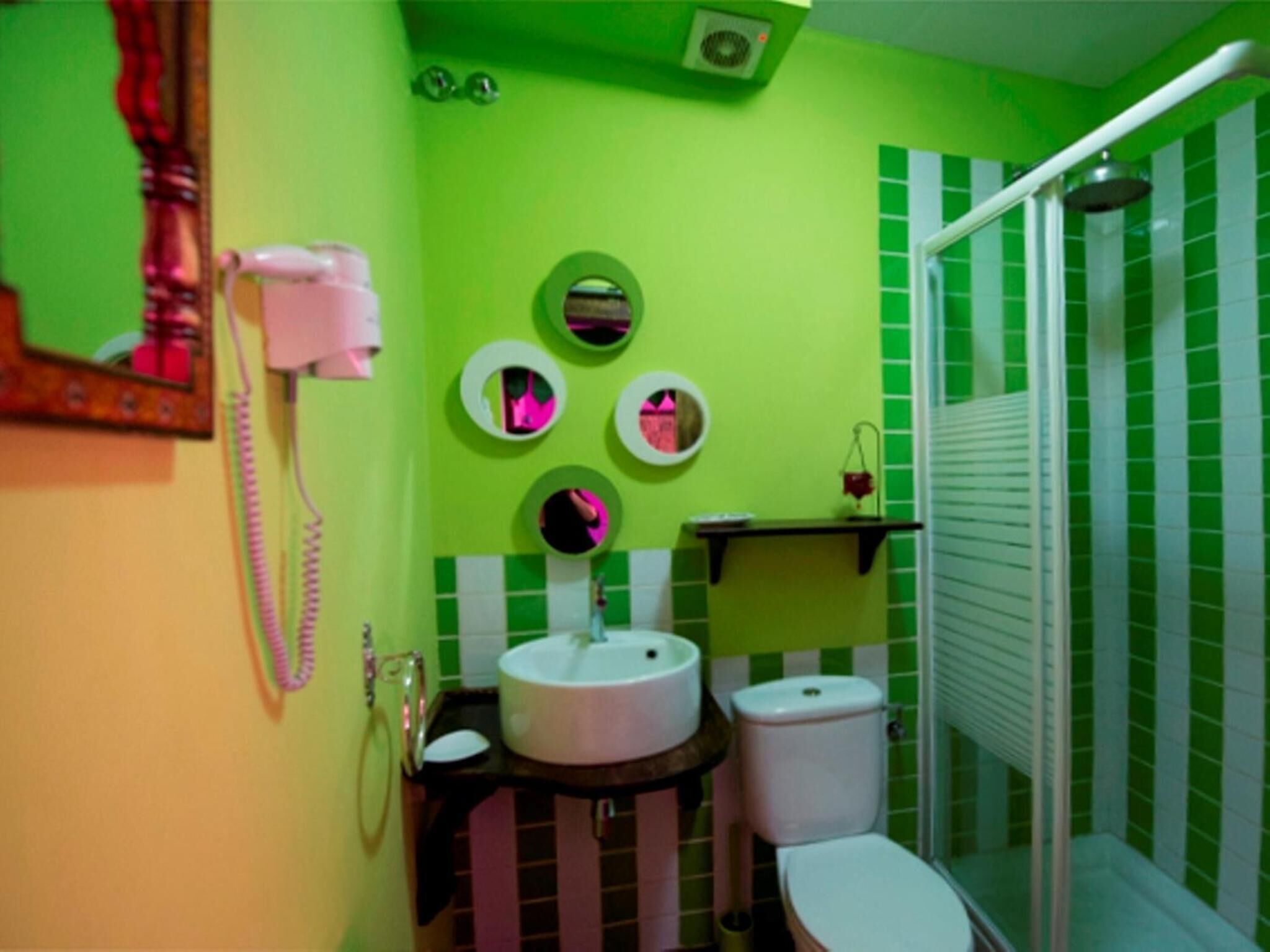 A bathroom with a green and white checkered wall, a white sink, a toilet, and a shower area.