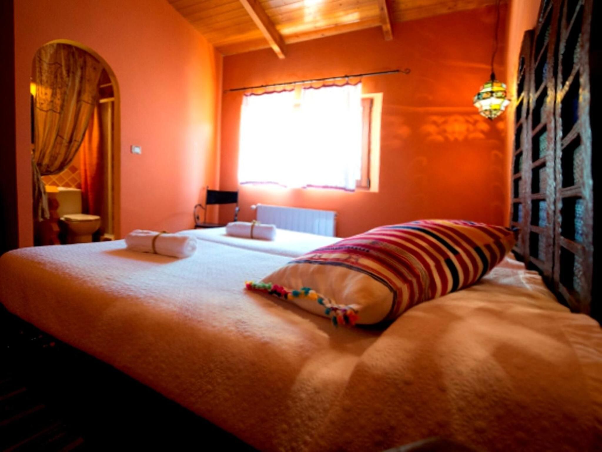 Un dormitorio con cama, ventana, radiador y cortina.