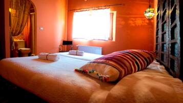 Un dormitorio con cama, ventana, radiador y cortina.