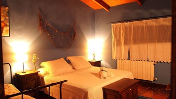 Un dormitorio acogedor con cama, mesitas de noche, una lámpara colgante y un ventanal con cortinas.