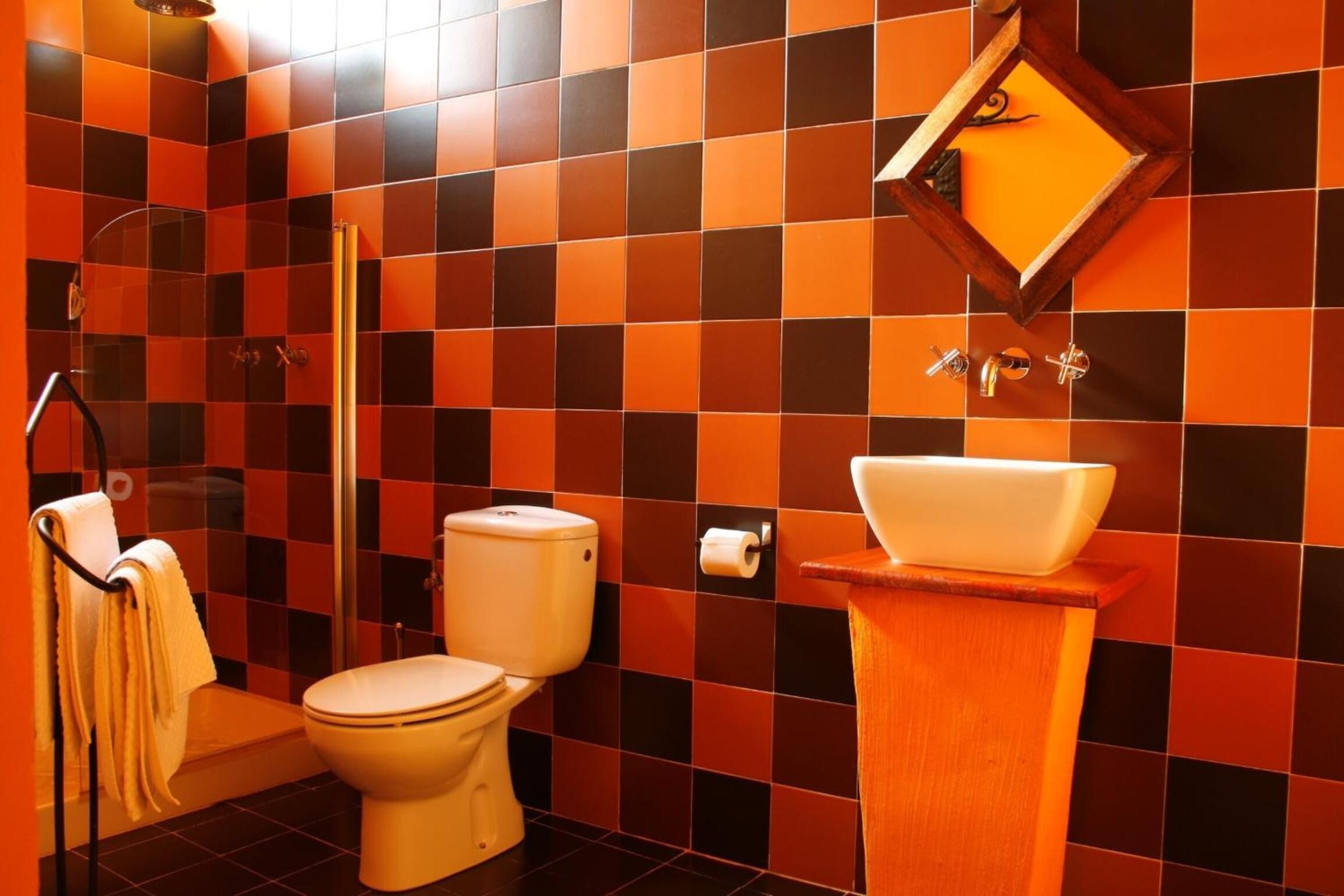 Ein Badezimmer mit Wänden aus Schachbrettfliesen, einer Toilette, einem Waschbecken und einer Dusche.