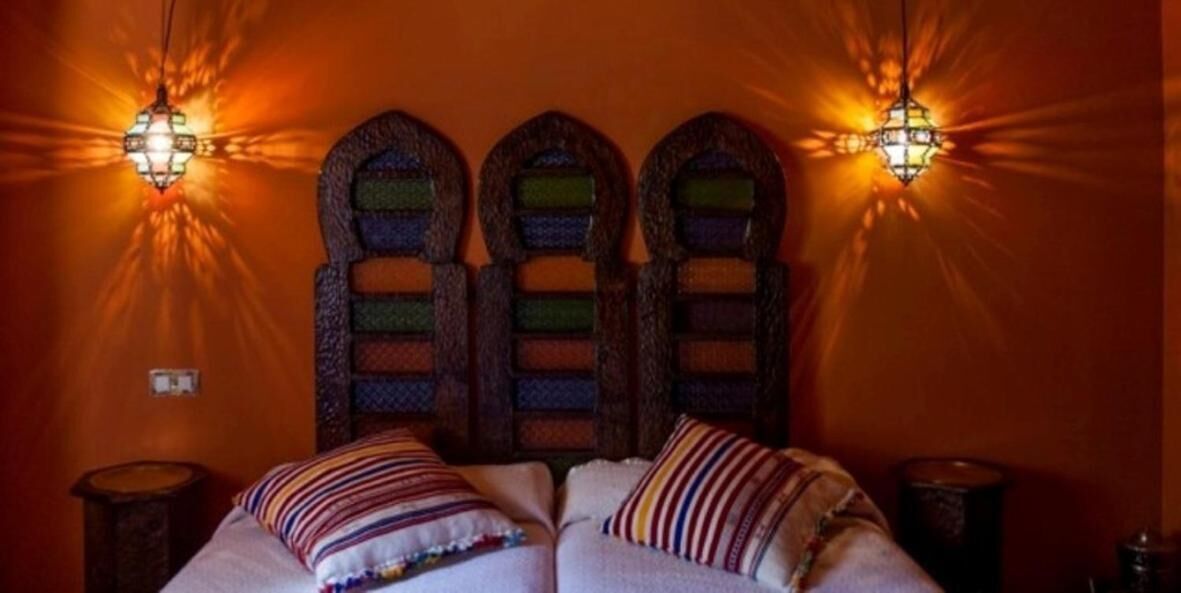 A room with a bed, two wall-mounted lamps, and a decorative wall panel.