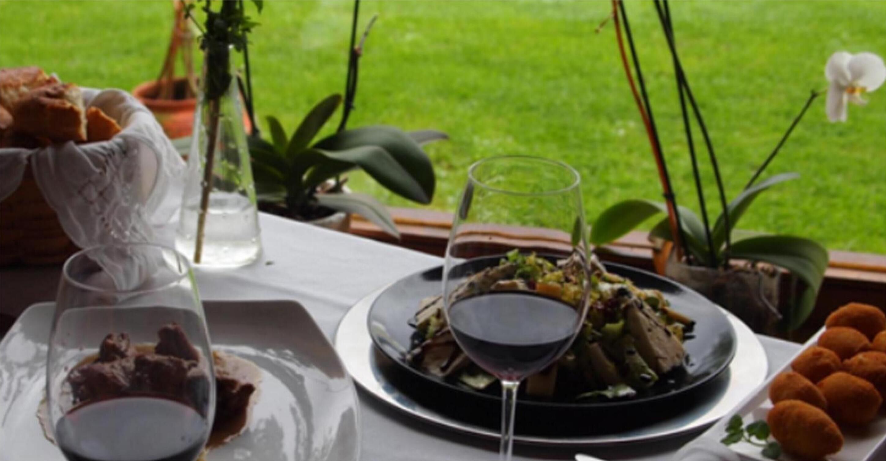 A dining table with a plate of food, a glass of red wine, and a glass of water.