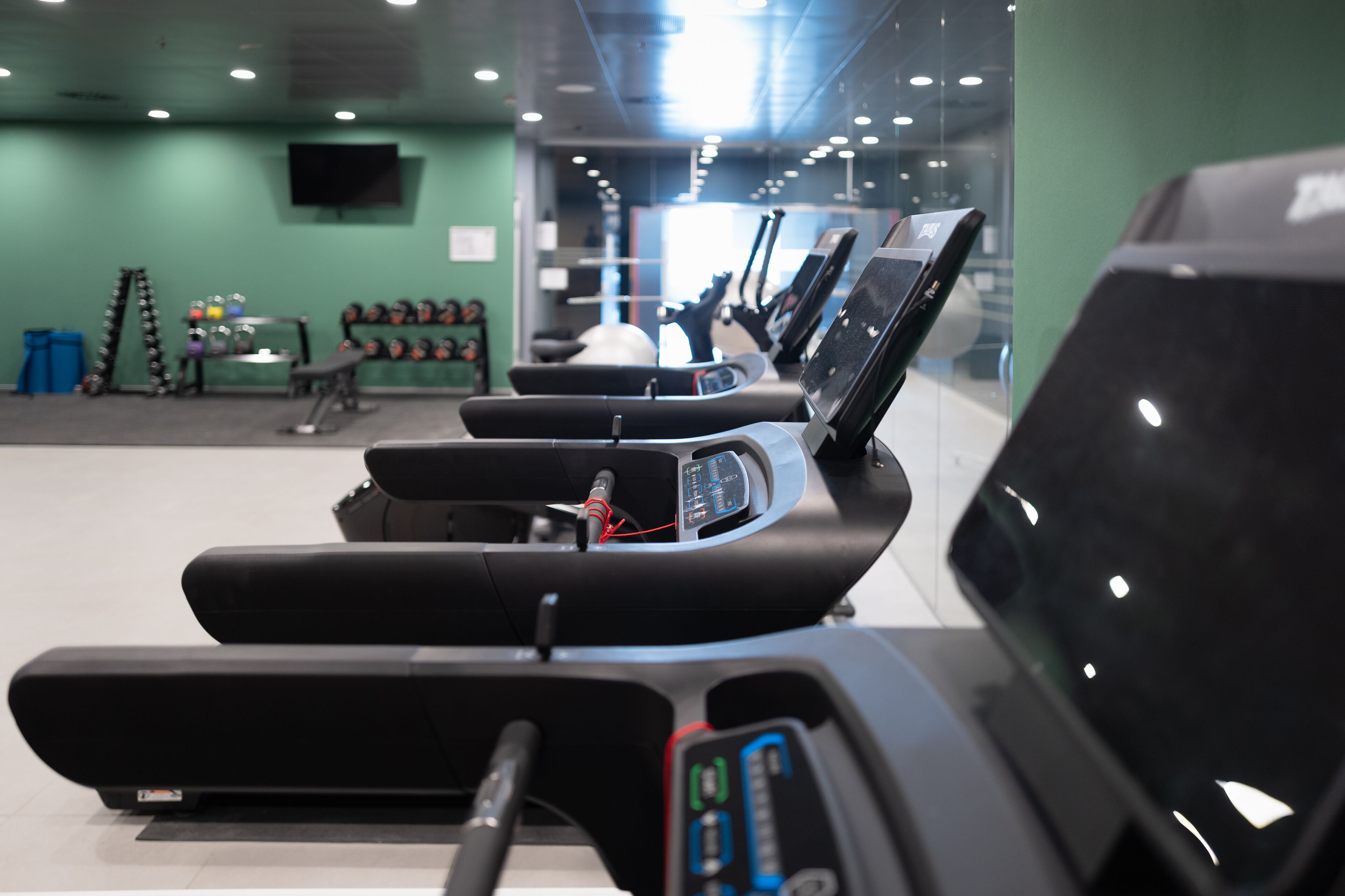 Een sportschool met loopbanden, fitnessballen en gewichten.