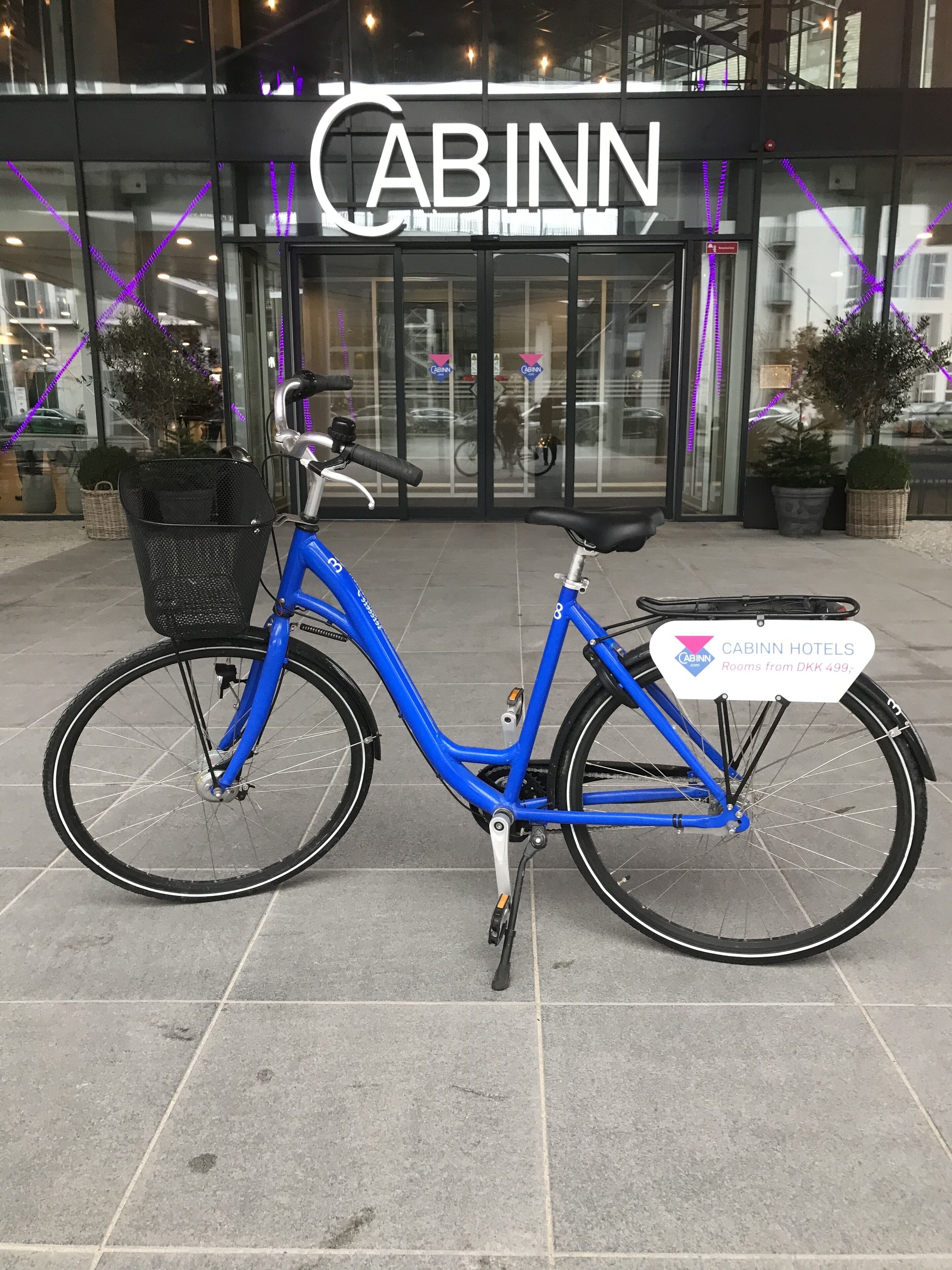 A blue bicycle parked in front of a building with the sign "CABINN".