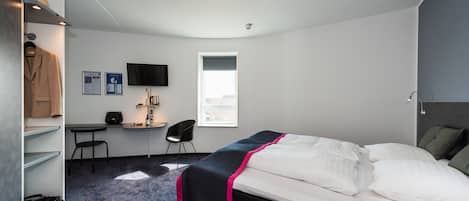 Une chambre d’hôtel équipée d’un lit, d’un bureau, d’une chaise, d’une armoire, d’une télévision et d’une fenêtre.