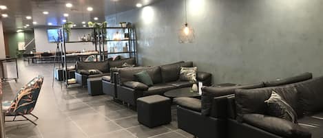 Un área de estar moderna con sofás de cuero, una mesa de centro y una pantalla de televisión.