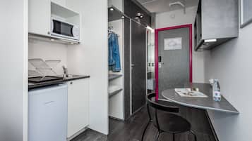 Cocina compacta con microondas, un refrigerador pequeño, un lavabo y una zona de comedor con mesa y sillas.