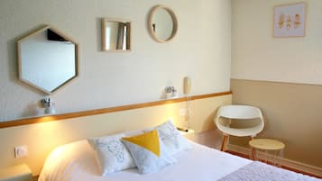 A hotel room with a bed, bedside table, lamp, mirror, and a small round table.