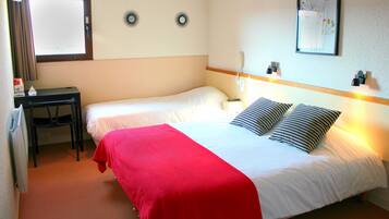 A hotel room with a bed, a desk, a chair, a window, and wall decorations.