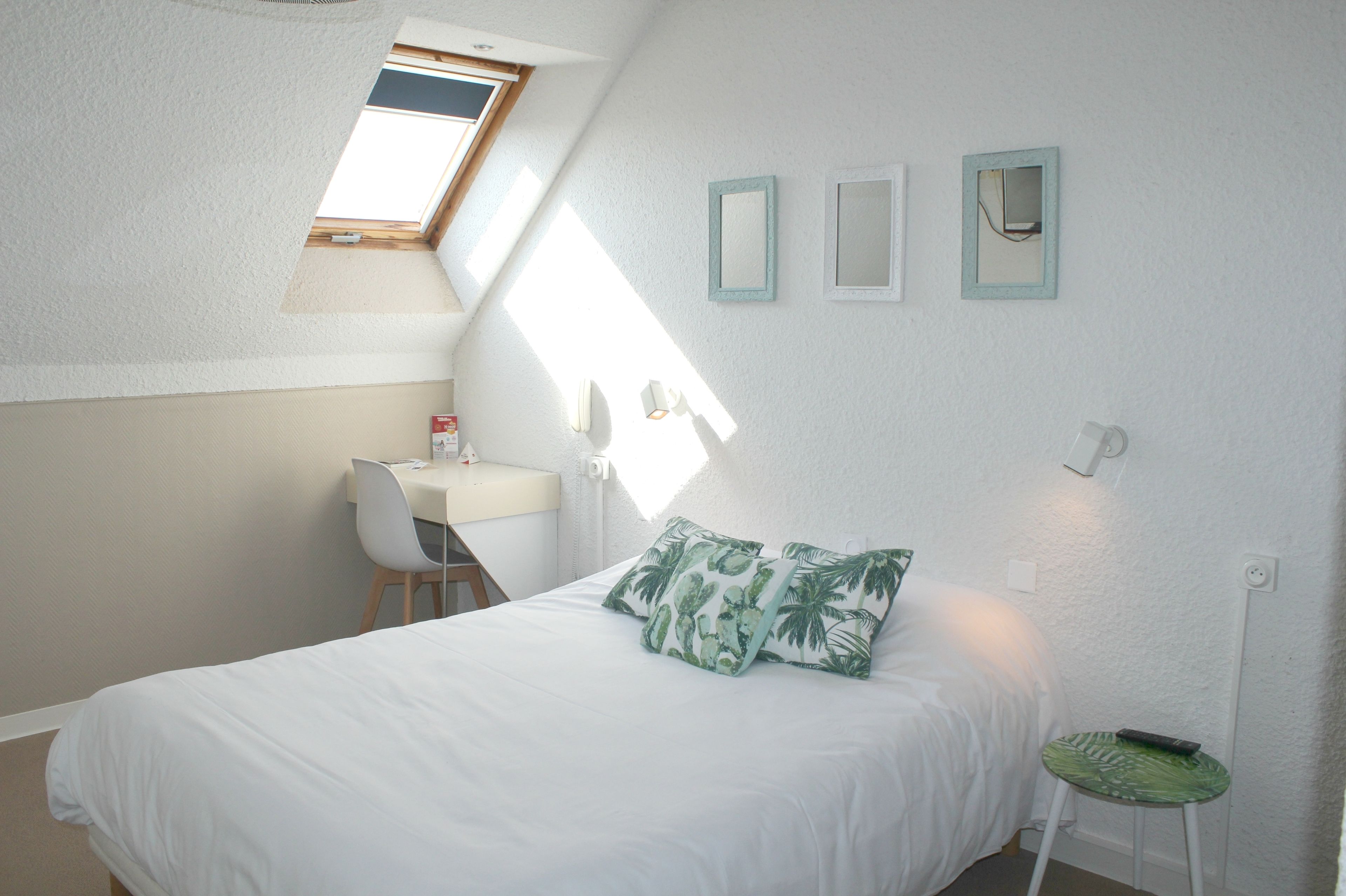 Un dormitorio con una cama, un escritorio y una silla. Una ventana proporciona luz natural.