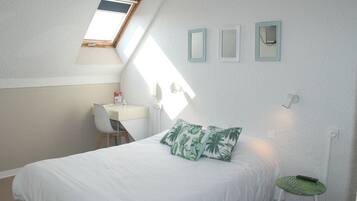 Un dormitorio con una cama, un escritorio y una silla. Una ventana proporciona luz natural.