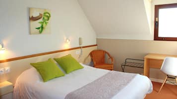 A bedroom with a bed, a chair, a desk, a wall-mounted phone, and a window.