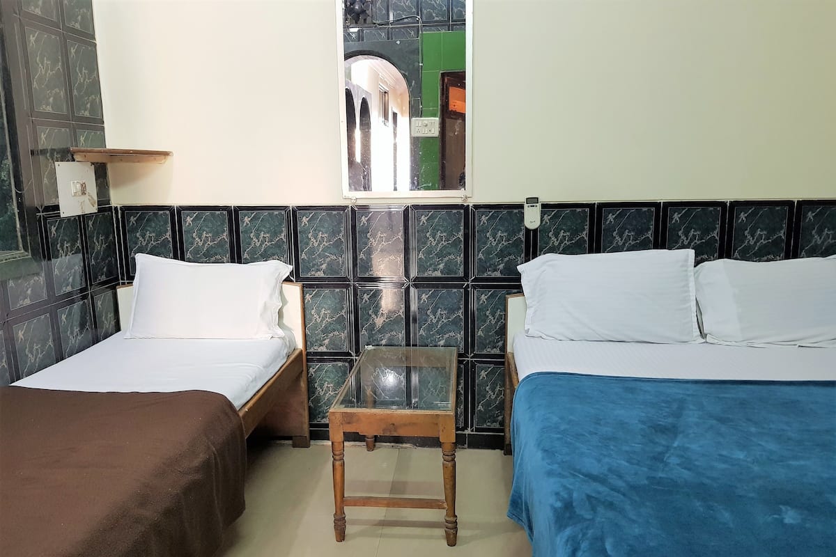 A room with two single beds, a small wooden table, and a mirror on the wall.