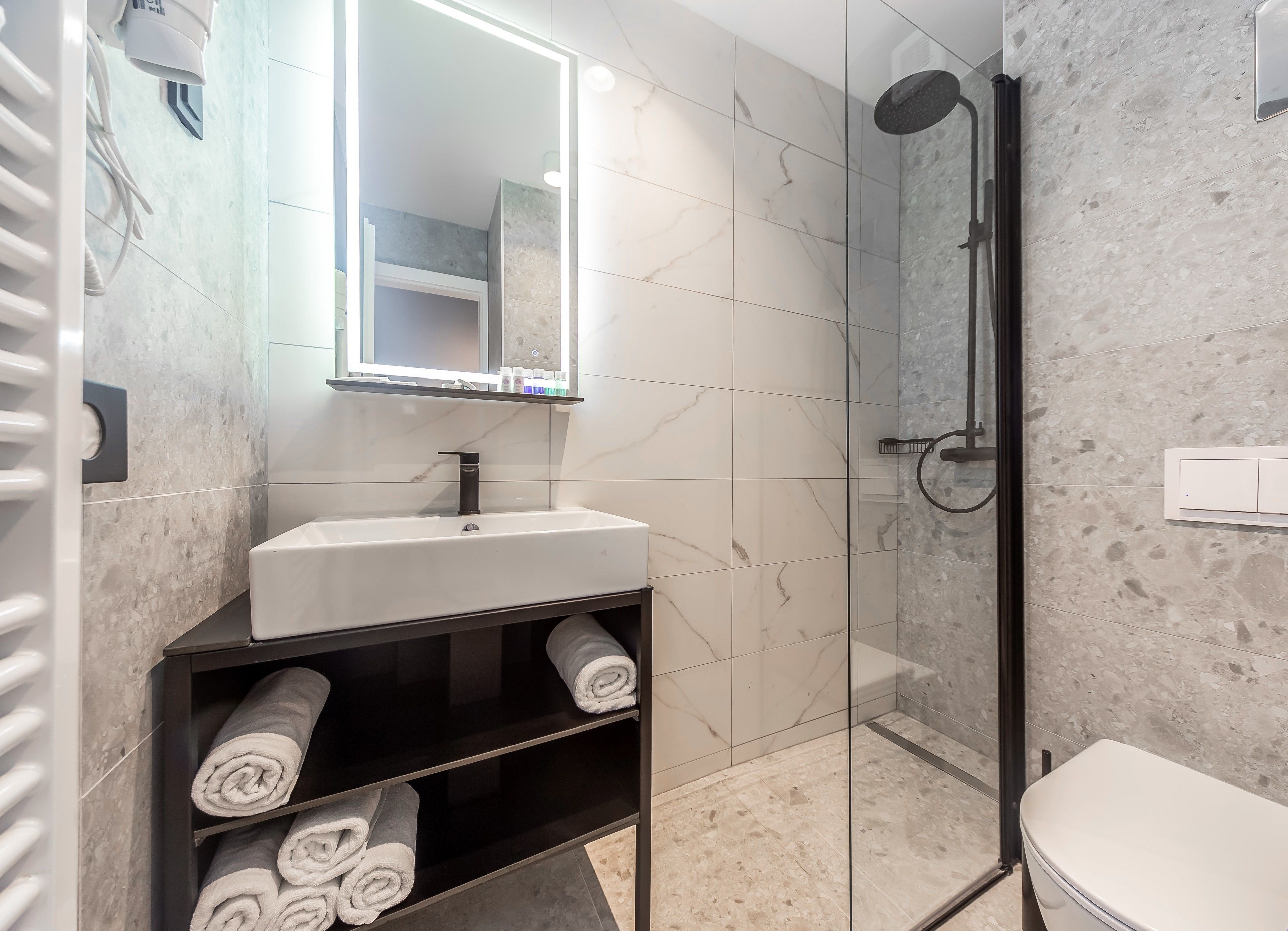 Une salle de bain moderne avec une douche à parois de verre, un lavabo blanc et un miroir au-dessus.