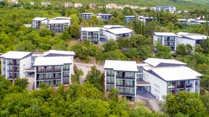 Ein moderner Wohnkomplex mit mehreren zweistöckigen Gebäuden, jedes mit Balkonen und großen Fenstern.