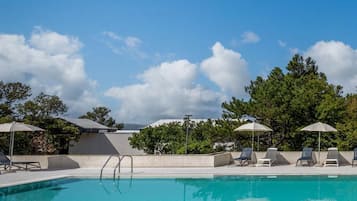 Una piscina al aire libre, sombrillas, sillones reclinables de piscina