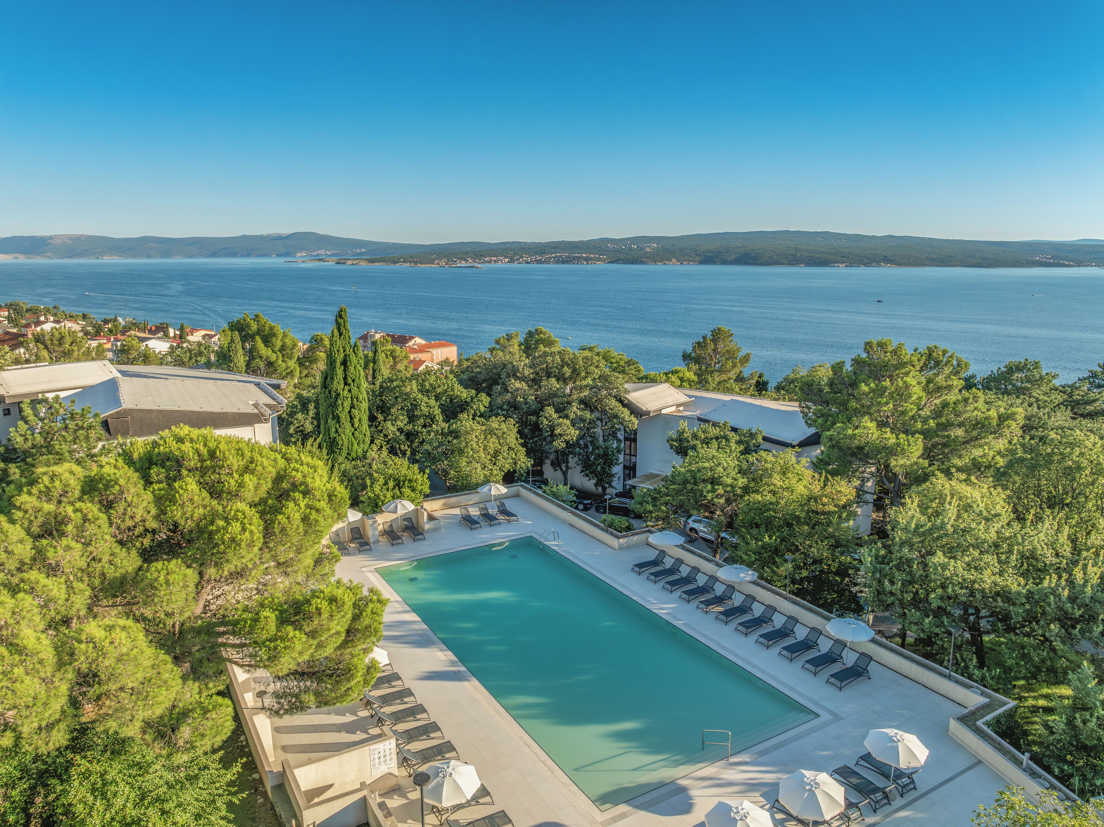Et resort med swimmingpool, liggestole og havudsigt.