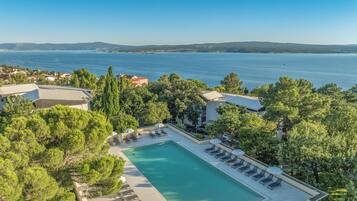 Et resort med swimmingpool, liggestole og havudsigt.