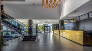 Eine geräumige Lobby mit moderner Treppe, einem Empfangsbereich und einem Glasgeländer, das auf den Bereich blickt.