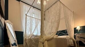 Una cama con dosel sobre cuatro postes, con dosel blanco y estructura de madera.
