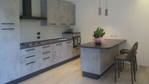 A modern kitchen with grey cabinets, a central island, and bar stools. - Frem SGV between Chianti Florence and Arezzo (San Giovanni Valdarno)