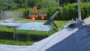 Two glasses of red wine on a glass table outdoors with a white umbrella and a metal chair. - Frem SGV between Chianti Florence and Arezzo (San Giovanni Valdarno)