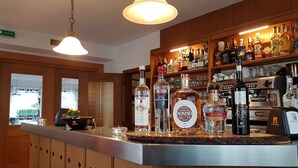 A bar area with a variety of liquor bottles, a coffee machine, and a wooden counter. - Pension Volgger (Rodengo)